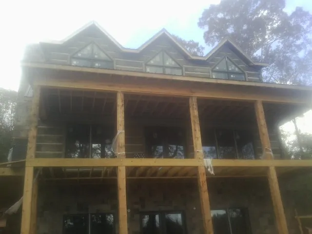 Dormers and porch framing on a large log home under construction — Roof Coating work by our crew in Western Springs