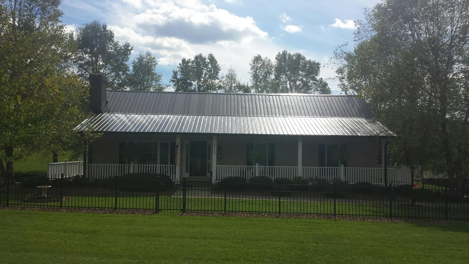 Gray metal roof on a brick ranch with a full width front porch — Gutter Guard Installation work by our crew in Western Springs