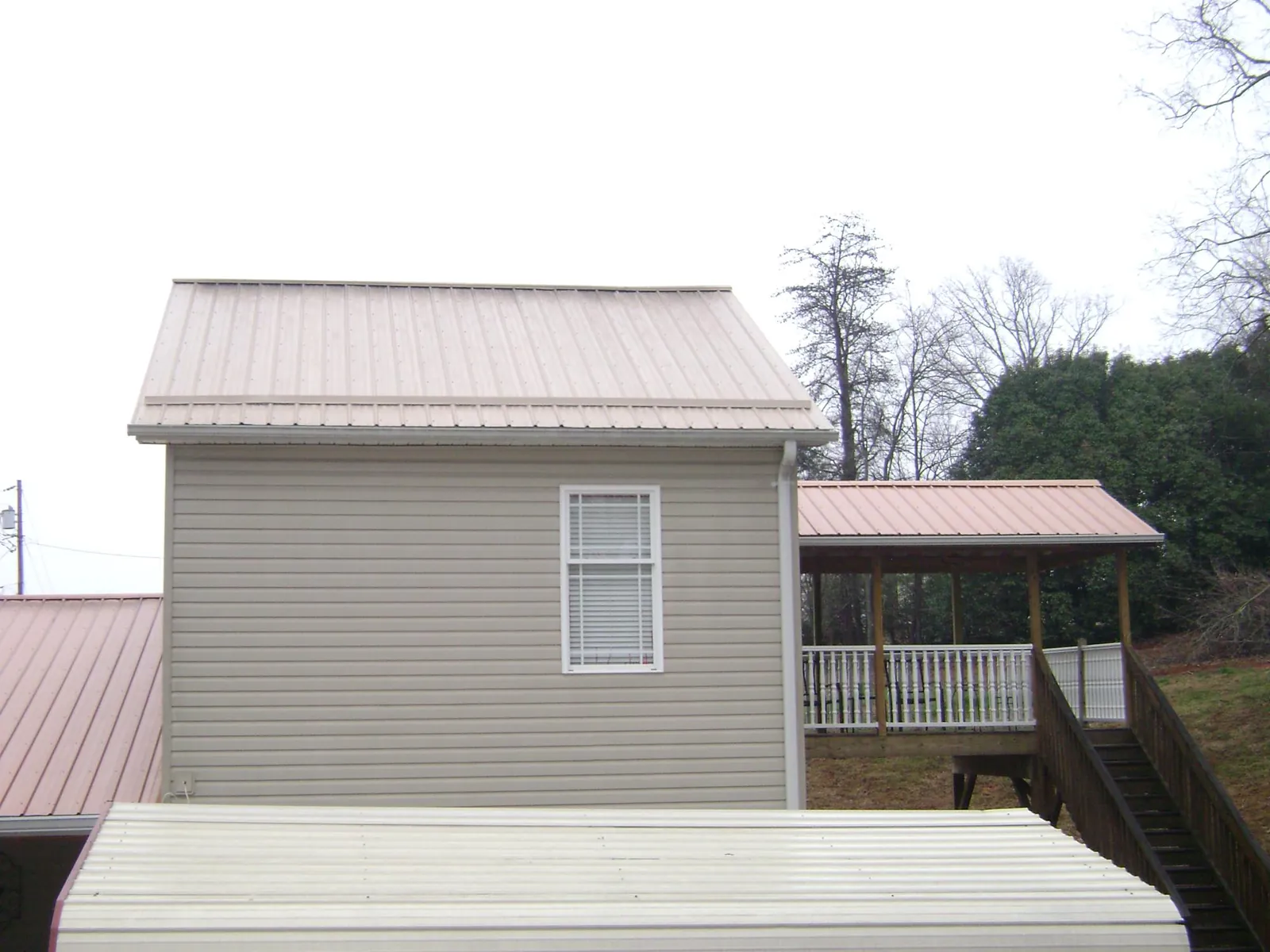 Tan metal roofs on a two story addition and attached porch, from a Roof Replacement job in Western Springs