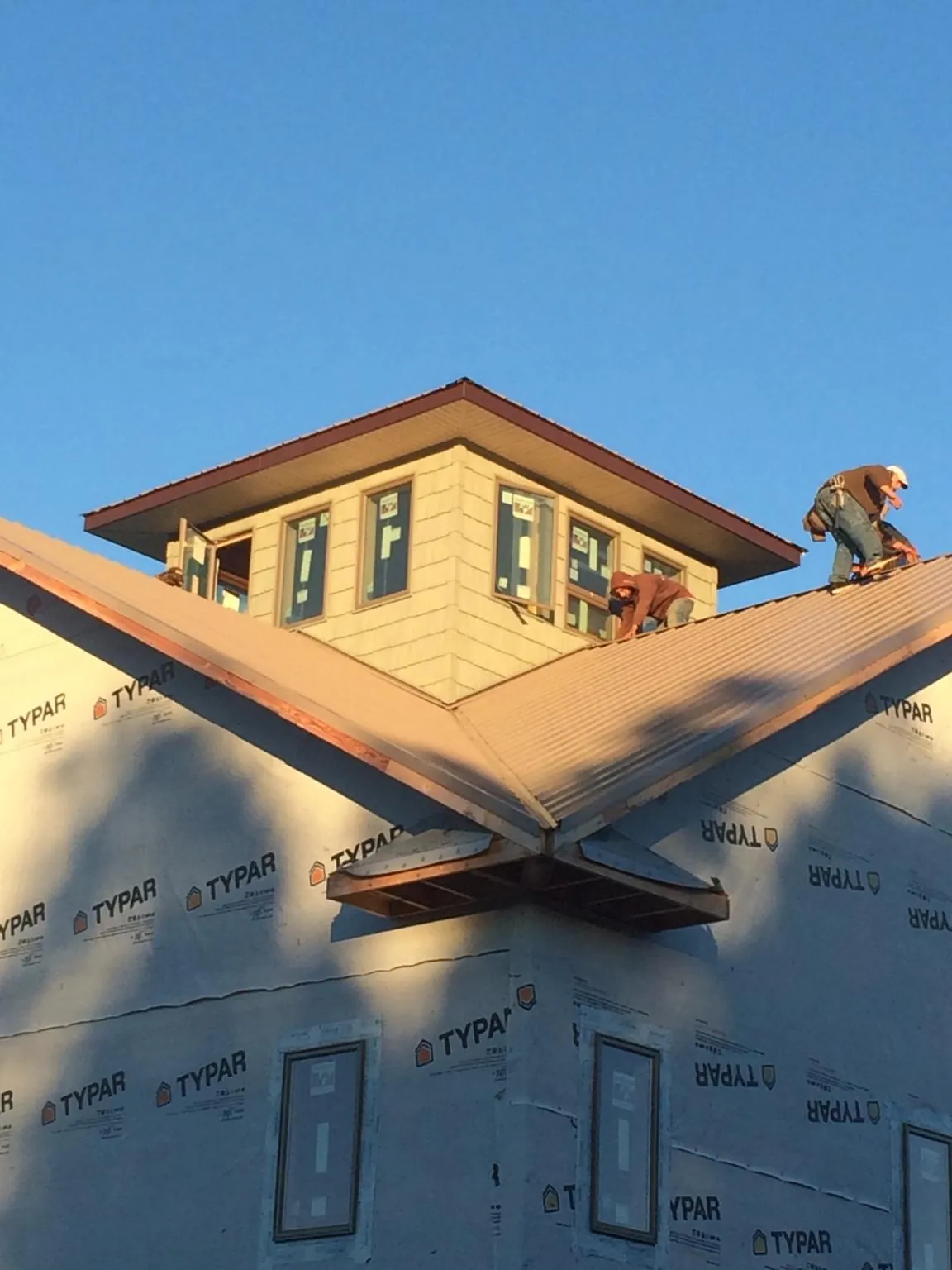 Roofers working around a rooftop cupola on a new metal roof at sunset — Roof Waterproofing in Western Springs by Roofing Brothers